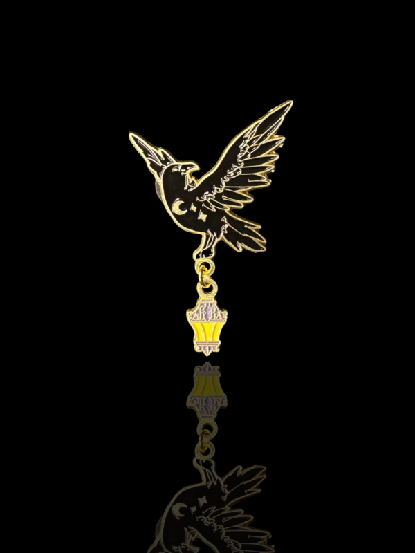 Pin goth corbeau noir avec lanterne dorée. Accessoire witchy et mystique pour veste, sac ou manteau.